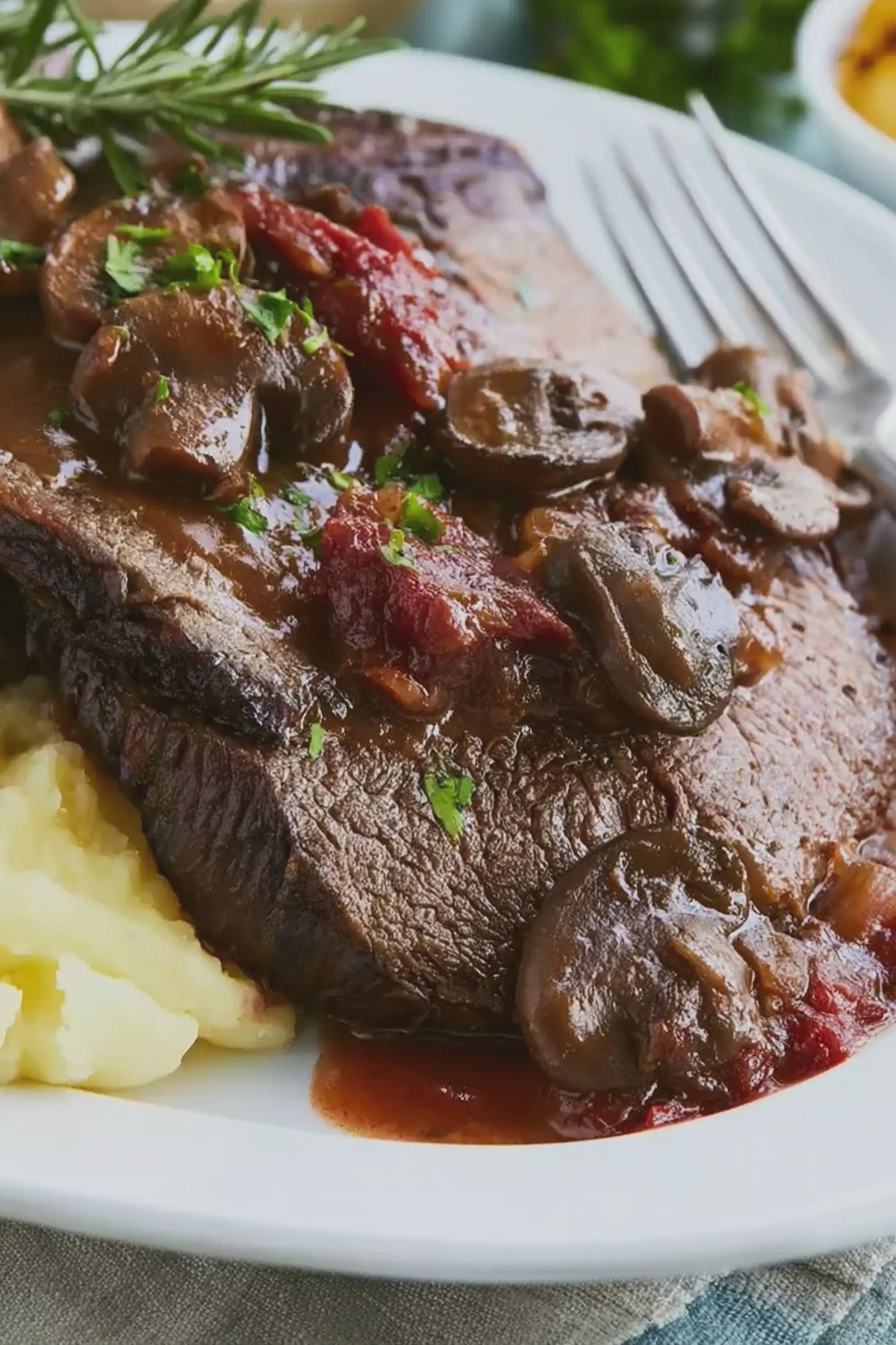 Geschmorter Rinderbraten mit Pilzen auf einem Teller, garniert mit frischen Kräutern.